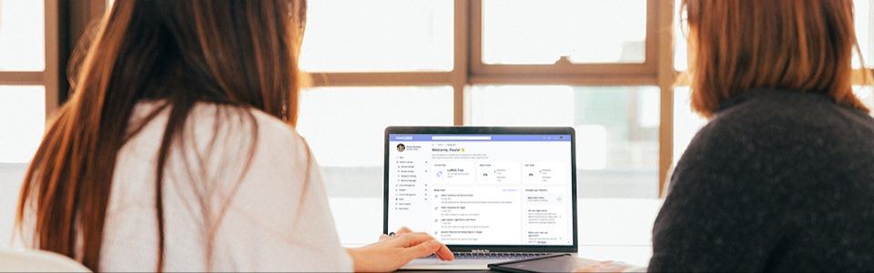 Zwei Frauen, die auf ihren Laptop starren, während sie ihre neue LoftOS-Plattform mit dieser Anleitung ganz einfach konfigurieren.