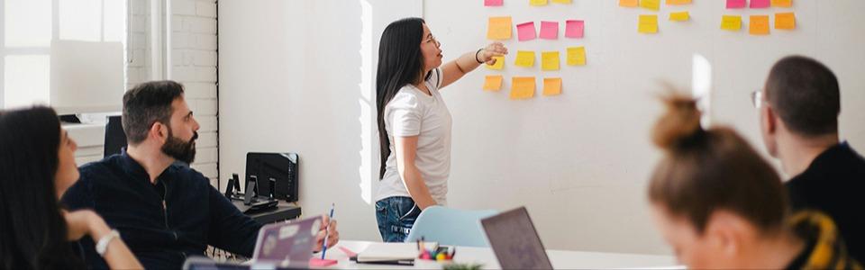 Eine Gruppe von Fachleuten sitzt zum Brainstorming in einer Wirtschaftsentwicklungsagentur zusammen und entwirft mit Haftnotizen Strategien.